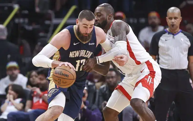 New Orleans Pelicans player drives aggressively with the ball while being defended by a Houston Rockets player