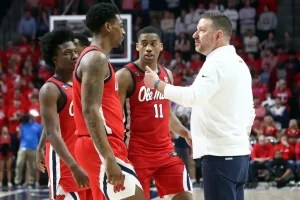 An Ole Miss basketball coach gives instructions to his players during a timeout.