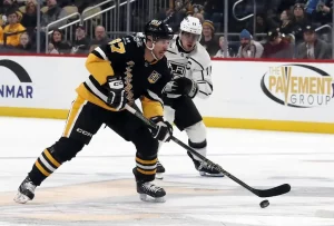 Pittsburgh Penguins forward Sidney Crosby controls the puck while being closely pursued by Los Angeles Kings captain.