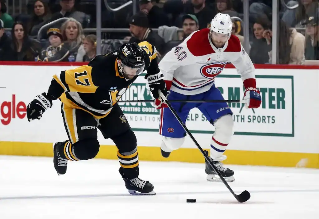 Pittsburgh Penguins player #17 battles a Montreal Canadiens player #40 for the puck.