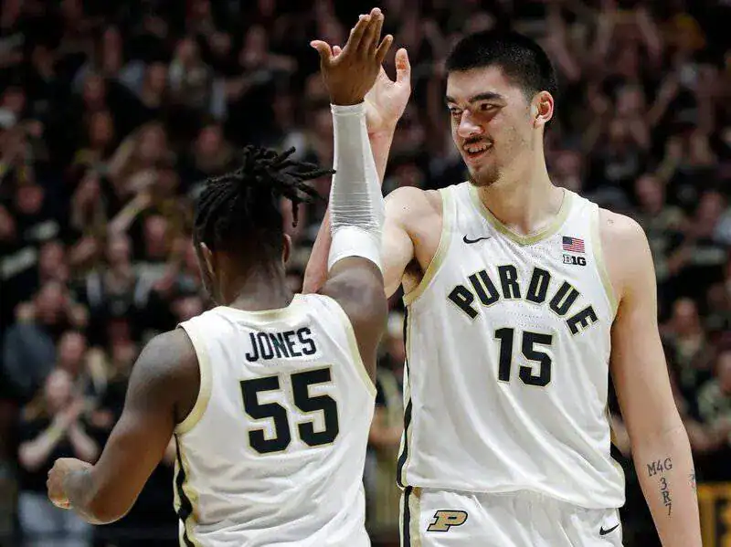 NCAAB 4 Purdue basketball players in white uniforms celebrate with a high five on the court.