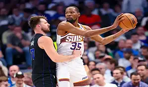 Phoenix Suns player holds the ball under pressure from a Houston Rockets defender during an NBA game.