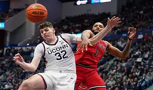 UConn Huskies player battles for the ball with St. John’s Red Storm defender during NCAA basketball game.