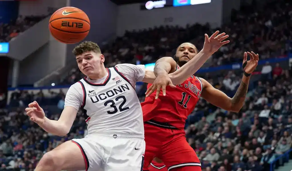 UConn Huskies player battles for the ball with St. John’s Red Storm defender during NCAA basketball game.