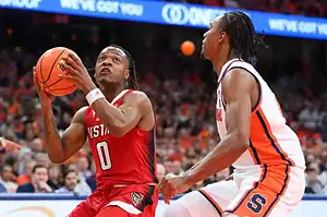 NC State Wolfpack basketball player prepares to shoot against Syracuse Orange defender.