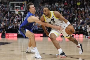 A Utah Jazz player drives toward the basket while being closely guarded by a defender.