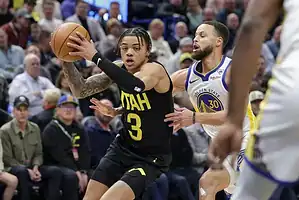 Utah player dribbles the ball while being guarded closely by Golden State’s Stephen Curry.