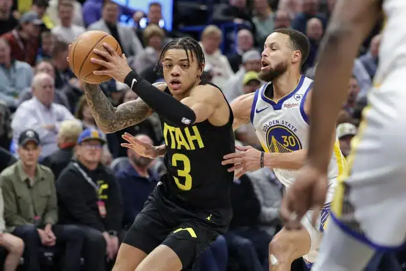 Utah player dribbles the ball while being guarded closely by Golden State’s Stephen Curry.