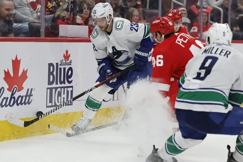 NHL 8 A Vancouver Canucks player controls the puck along the boards.