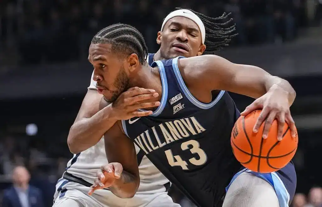 A Villanova basketball player dribbles the ball in a dynamic moment during a game, showcasing athleticism and intensity.