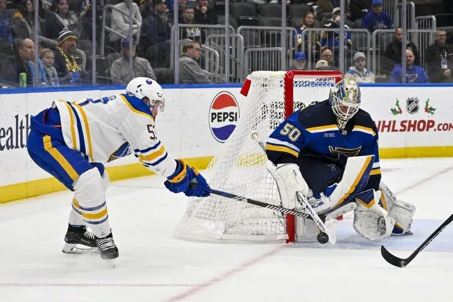 nhl player facing off against the rival team goalie for the puck