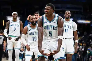 Minnesota Timberwolves players celebrate as Anthony Edwards flexes after a big play.