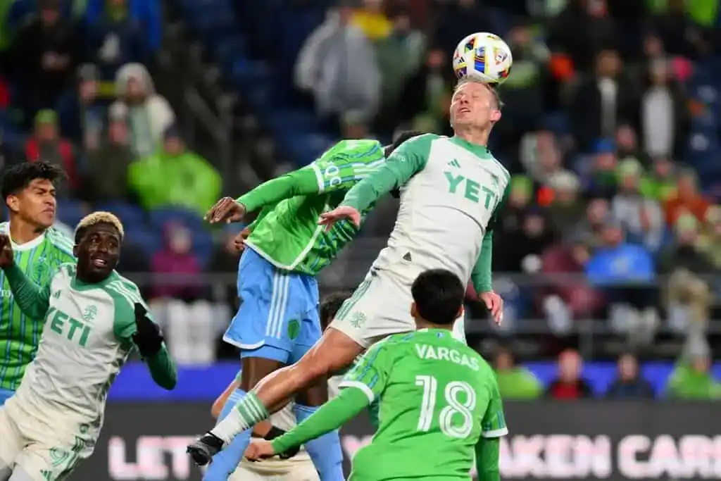 Austin FC player leaps to head the ball during a match against St. Louis City SC.