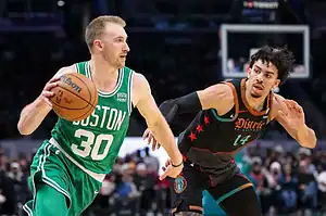 Boston Celtics player driving forward with the ball while being guarded by a Washington Wizards player in an NBA matchup.