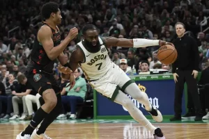 A Boston player drives aggressively to the basket while being closely guarded by a defender.