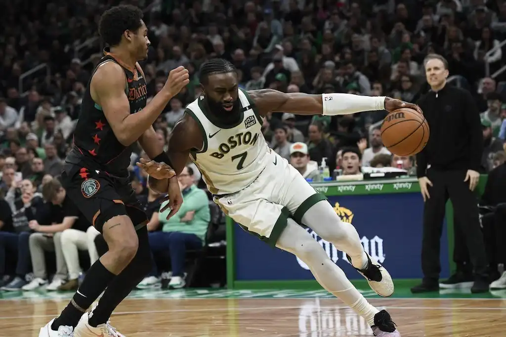A Boston player drives aggressively to the basket while being closely guarded by a defender.