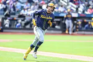 Milwaukee Brewers player in navy and yellow uniform sprints around the base paths during a game.