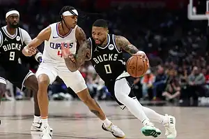 Milwaukee Bucks player drives to the basket while being defended closely by a Los Angeles Clippers player during an NBA game