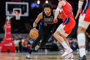 Detroit Pistons player Cade Cunningham dribbling the basketball past a Washington Wizards defender during an NBA game.