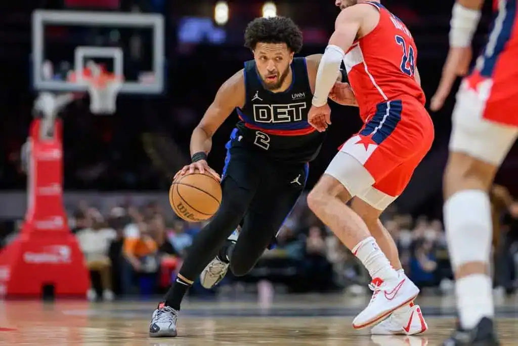 Detroit Pistons player Cade Cunningham dribbling the basketball past a Washington Wizards defender during an NBA game.