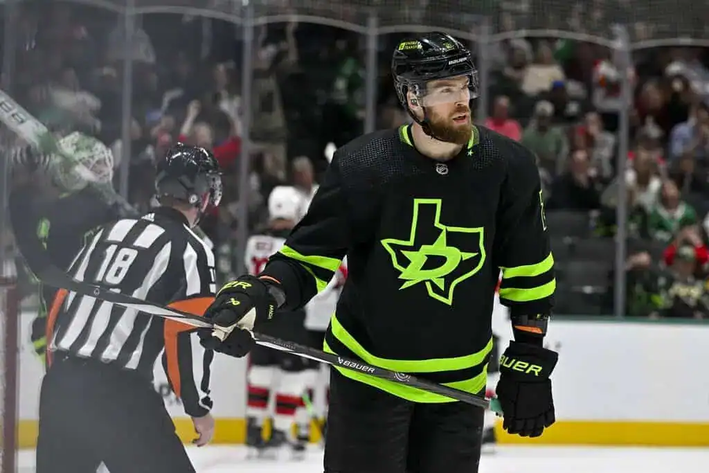 Dallas Stars hockey player wearing a black jersey with neon green accents, holding his stick during NHL action.