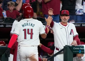Gabriel Moreno of the Arizona Diamondbacks high-fives a coach near the dugout after a play.