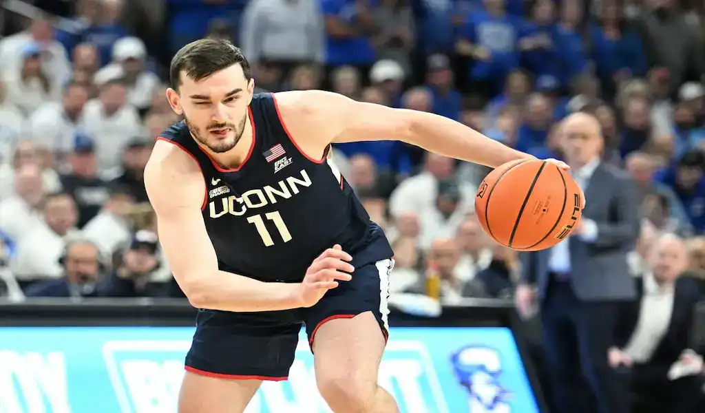 NCAAB 2 UConn Huskies player dribbling the basketball during a college game against the Providence Friars.