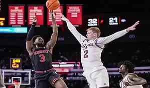 Georgia Bulldogs guard takes a jump shot over Xavier Musketeers defender during NCAA basketball matchup.