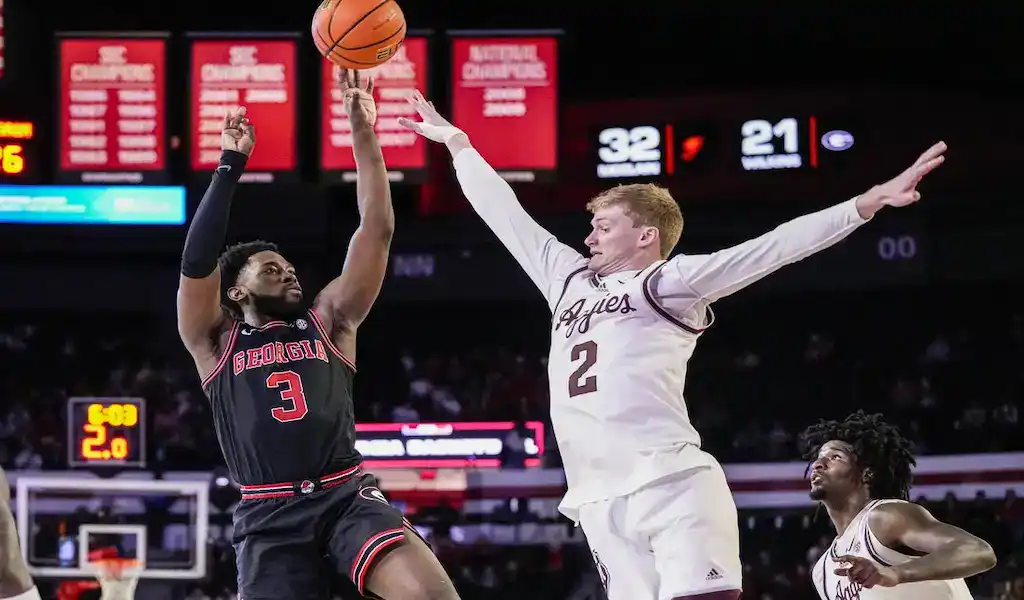 Georgia Bulldogs guard takes a jump shot over Xavier Musketeers defender during NCAA basketball matchup.