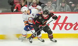 New York Islanders and Ottawa Senators players battling for the puck during an NHL game.