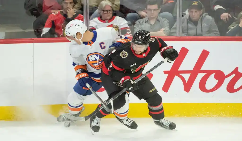 New York Islanders and Ottawa Senators players battling for the puck during an NHL game.