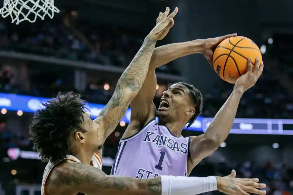 NCAAB 8 ansas State basketball player drives to the hoop under heavy defensive pressure