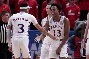 Kansas Jayhawks basketball players celebrate on the court during an NCAA game.