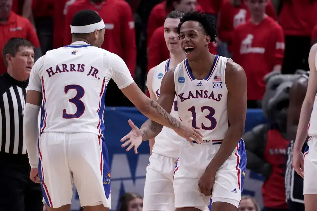 Kansas Jayhawks basketball players celebrate on the court during an NCAA game.