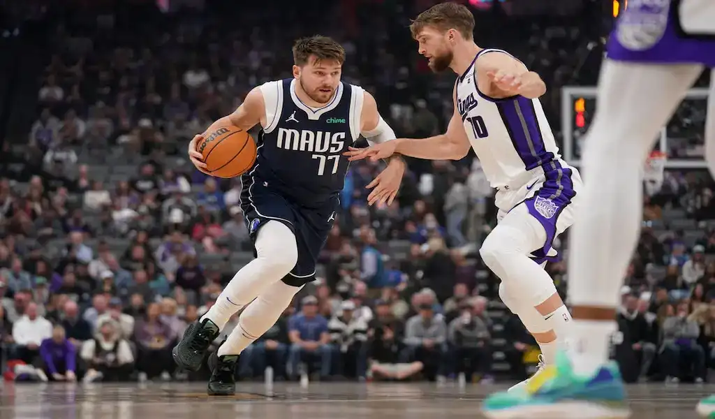 Dallas Mavericks player drives to the basket while defended by a Sacramento Kings player during an NBA game.