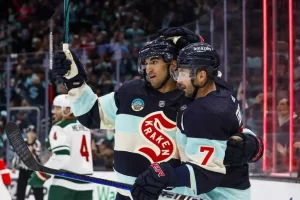 Two Seattle Kraken hockey players celebrate on the ice.