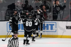 LA Kings hockey players celebrate near the glass.