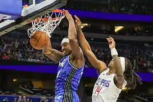 Orlando Magic player dunks against Clippers defender.