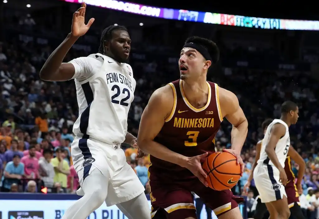 NCAAB 9 A Minnesota Golden Gophers basketball player drives toward the basket while closely guarded by a defender.