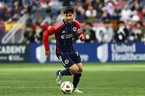 New England Revolution player dribbles the ball during an MLS match.