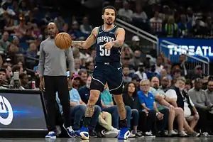 Orlando Magic player wearing number 50 dribbling the ball at midcourt while surveying the play during an NBA game.