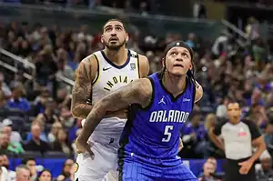 Orlando Magic and Indiana Pacers players battle for position under the basket during an NBA game.