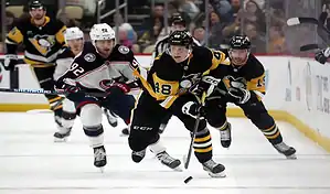 Pittsburgh Penguins and Columbus Blue Jackets players compete during a fast-paced hockey game on the ice.