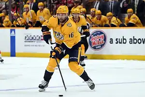 Nashville Predators player handling the puck while skating forward during an NHL game.