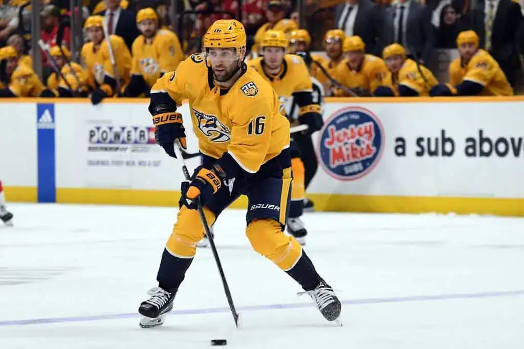 Nashville Predators player handling the puck while skating forward during an NHL game.