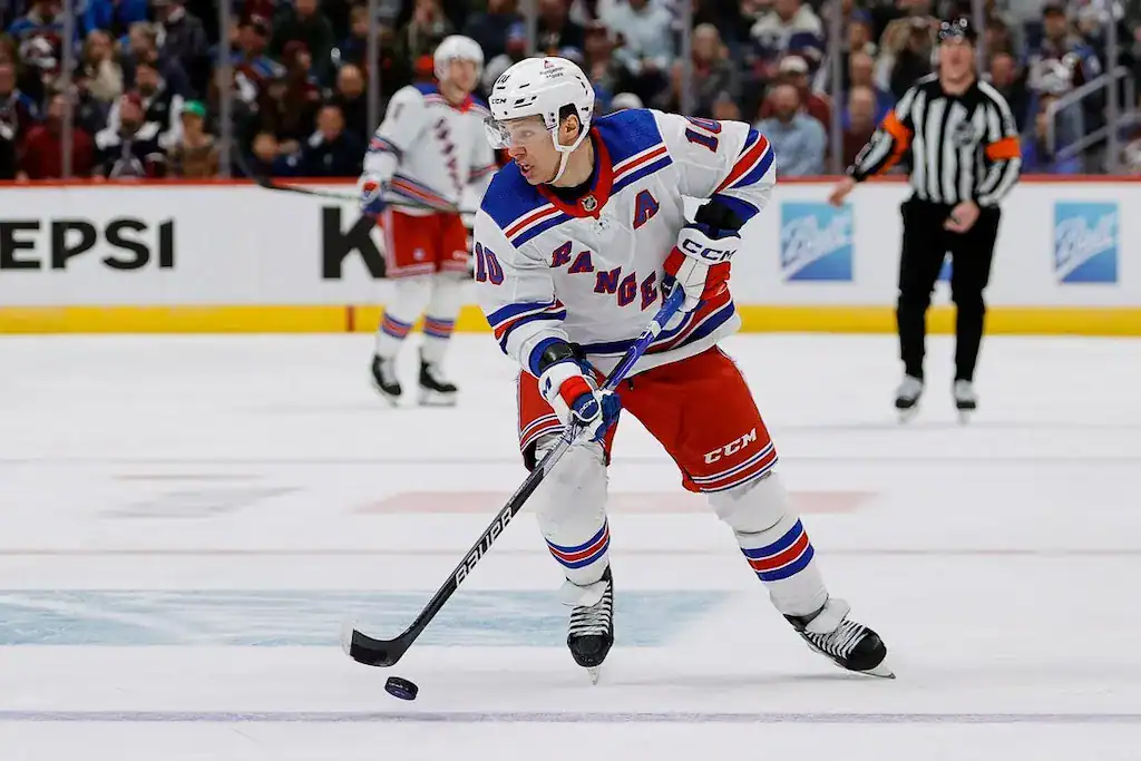 New York Rangers hockey player #10, handling the puck during a game.