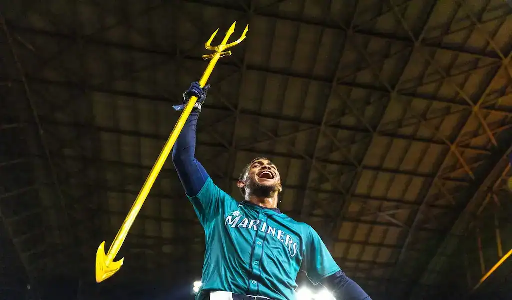 9 Seattle Mariners player celebrates with golden trident under stadium lights during matchup against Boston Red Sox on March 31, 2024.