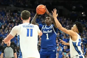 Seton Hall player attempts a jump shot while being defended by two players.
