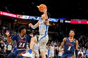 Memphis Tigers basketball player driving to the basket against UTSA defenders.