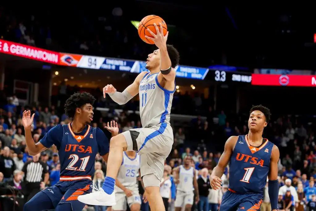 Memphis Tigers basketball player driving to the basket against UTSA defenders.